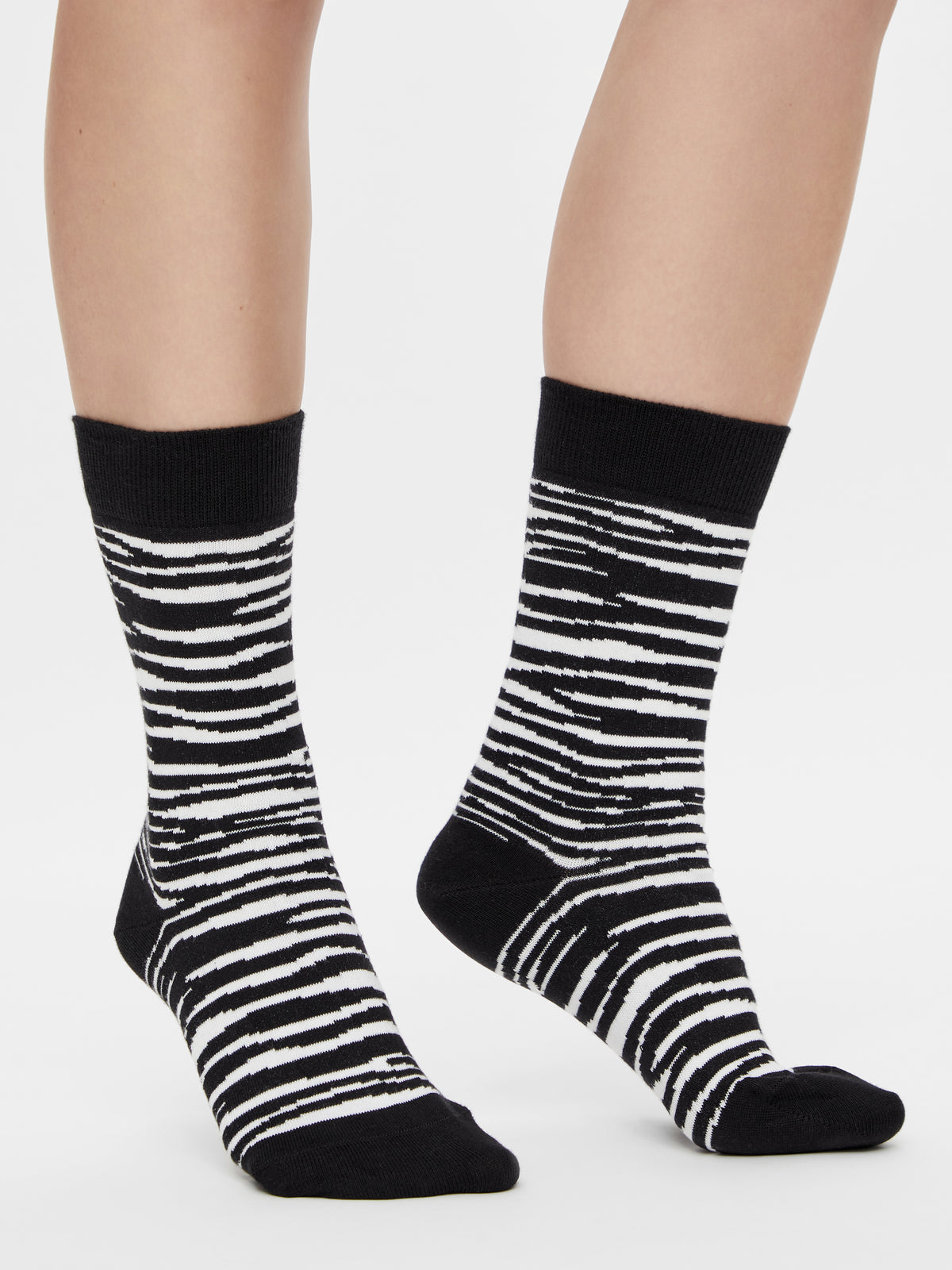 Schwarz-weiße Zebra Socken mit klassischem Animal Print am Fuß getragen.