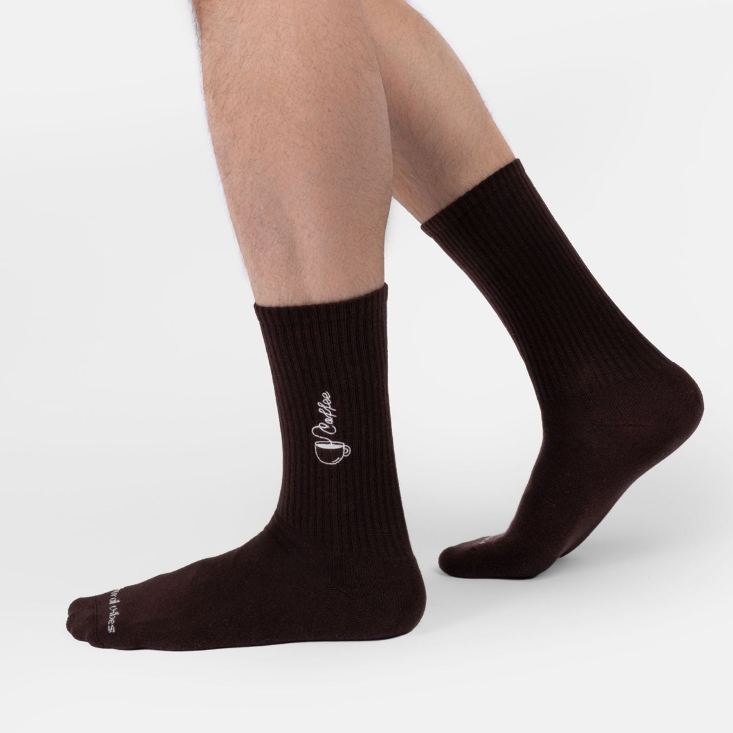 Person trägt dunkelbraune Bio-Tennissocken mit Kaffee-Stickerei im Alltag.