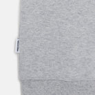 Detailansicht des gerippten Saums und gewebten Logo-Labels am hellgrauen Bio-Baumwoll-Sweater Panda. 